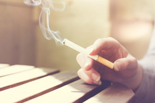 Mão segurando um cigarro aceso